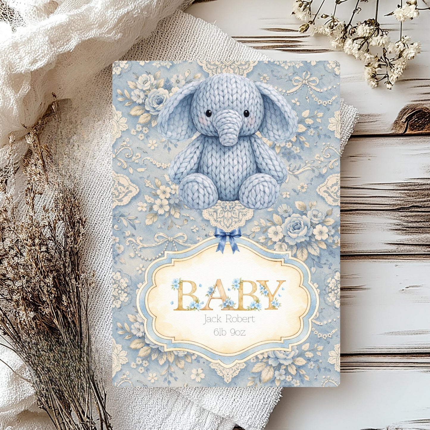Decorative baby card with a knitted elephant on a floral patterned background