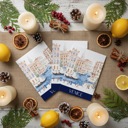 Three Christmas cards of Venice with candles, lemons, and pine cones on a wooden surface.