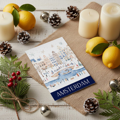 Greeting card with Amsterdam at Christmas illustration surrounded by candles, lemons, and pine cones on a wooden surface.