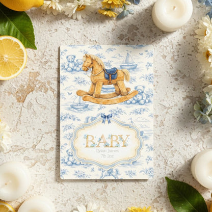 Personalised baby card with rocking horse design on a decorative surface with lemons and flowers.