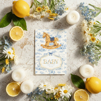 Baby card with rocking horse design surrounded by lemons, candles, and flowers on a textured surface